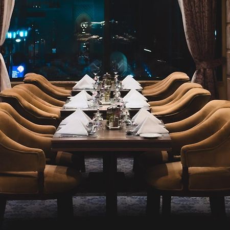 Madinah Hilton Hotel Medina Exterior photo The photo shows a long dining table set for a meal, with several elegant chairs arranged around it. Each place setting features a folded white napkin and shiny silverware, and there are decorative items, possibly small vases or candle holders, on the