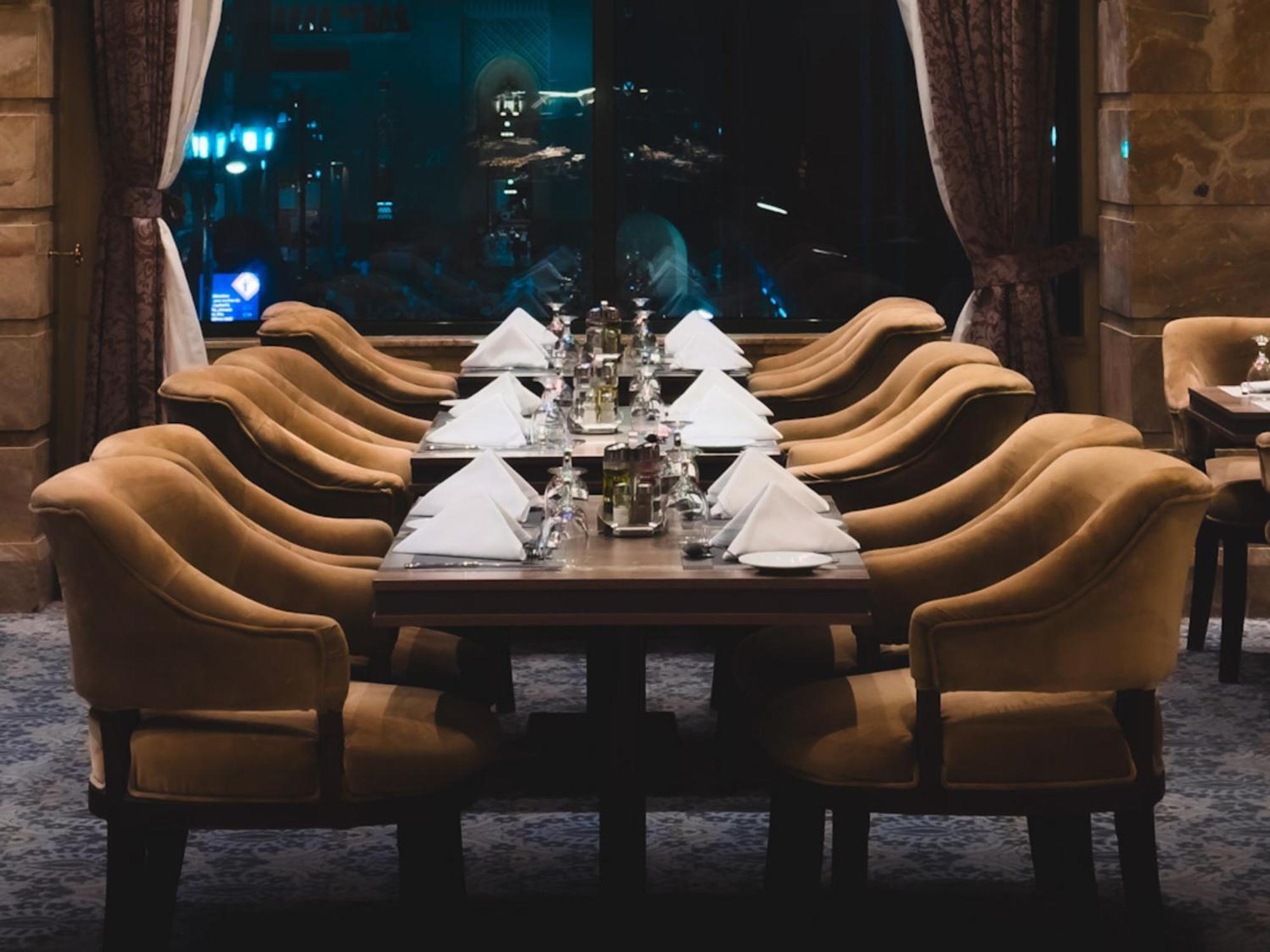 Madinah Hilton Hotel Medina Exterior photo The photo shows a long dining table set for a meal, with several elegant chairs arranged around it. Each place setting features a folded white napkin and shiny silverware, and there are decorative items, possibly small vases or candle holders, on the