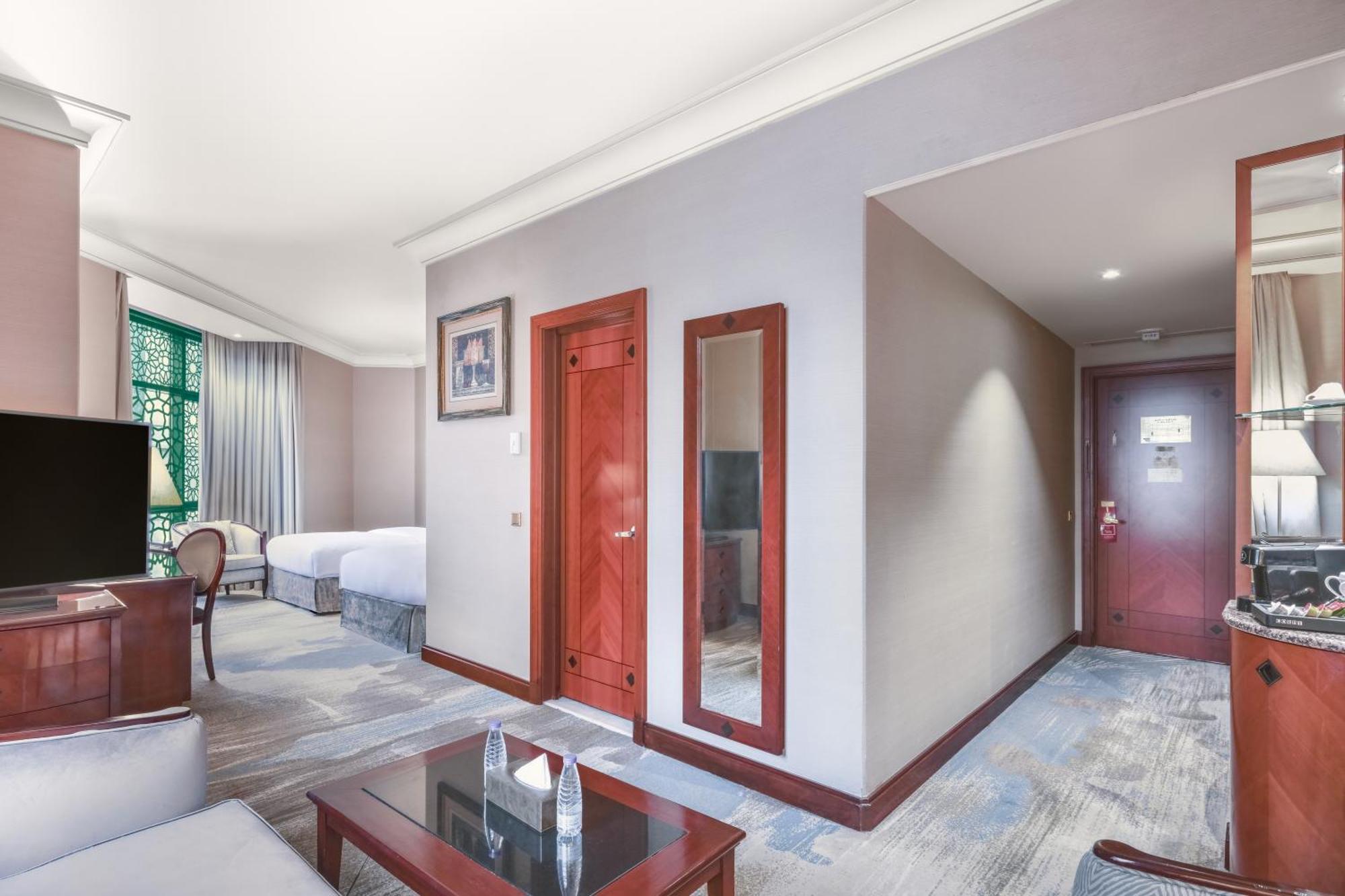 Madinah Hilton Hotel Medina Exterior photo The photo shows a hotel room interior. In the foreground, there is a coffee table with a couple of items on it, possibly tissue boxes. To the left, there is a sofa or seating area. The walls are painted in neutral tones, and there is a large mirror n
