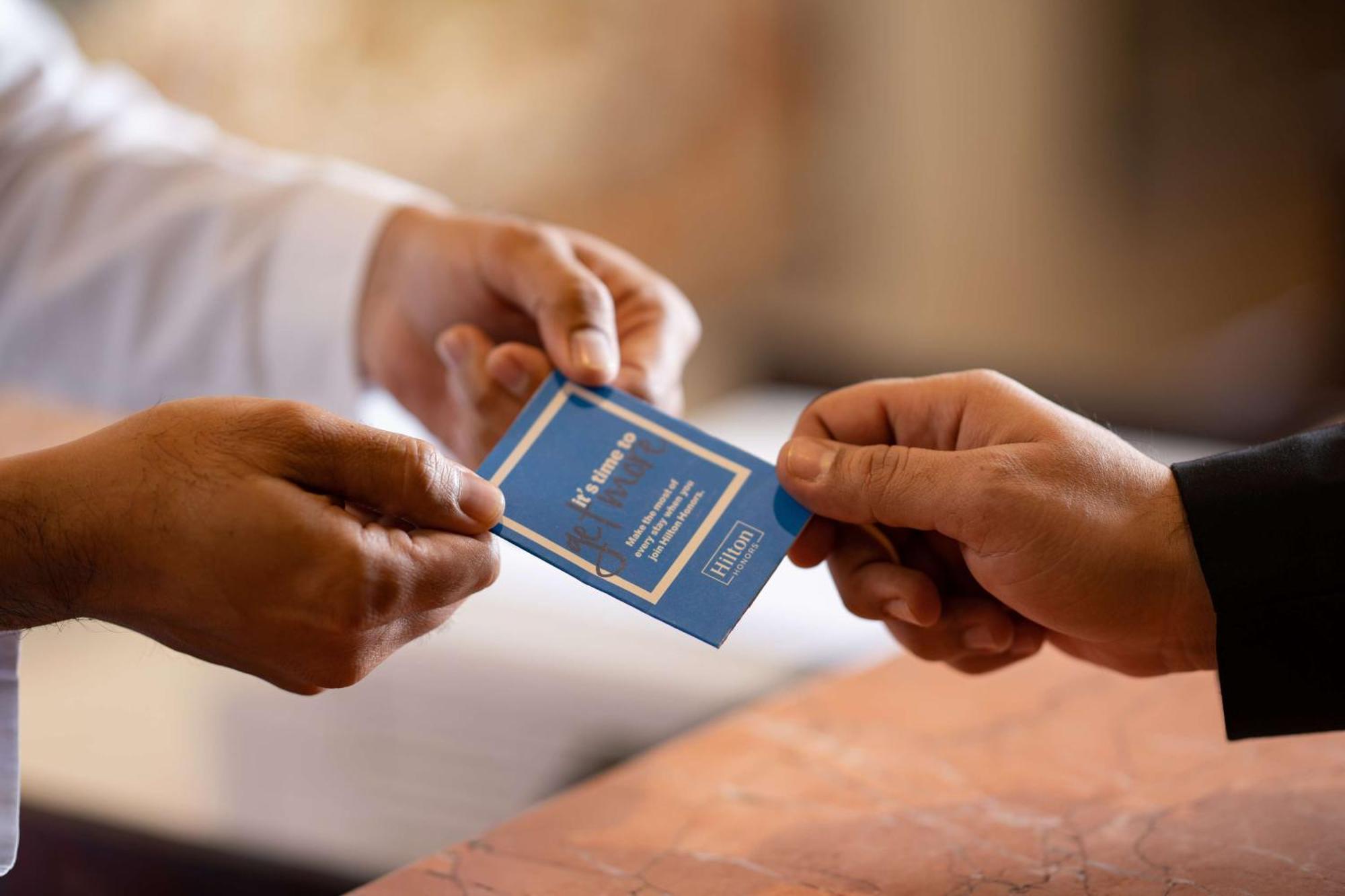 Madinah Hilton Hotel Medina Exterior photo The photo shows two hands exchanging a small blue card. One hand, presumably belonging to a person in a uniform, is offering the card, while the other hand is reaching out to receive it. The background appears to be a well-lit indoor space, possibly 
