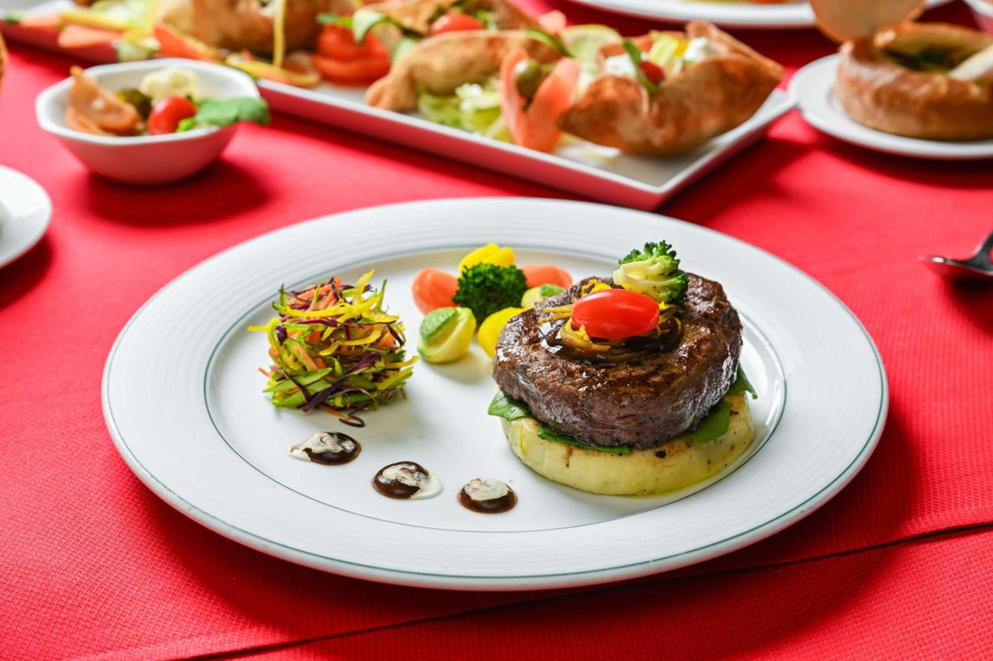 Madinah Hilton Hotel Medina Exterior photo The photo shows a beautifully plated dish featuring a piece of beef, likely a steak, resting on a bed of mashed potatoes. The beef is garnished with colorful vegetables, including small tomatoes and broccoli. Next to the meat, there is a decorative a